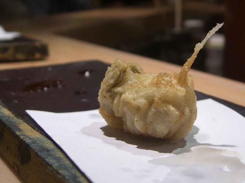 A single tempura-battered oyster on white paper at a Japanese restaurant in South Melbourne